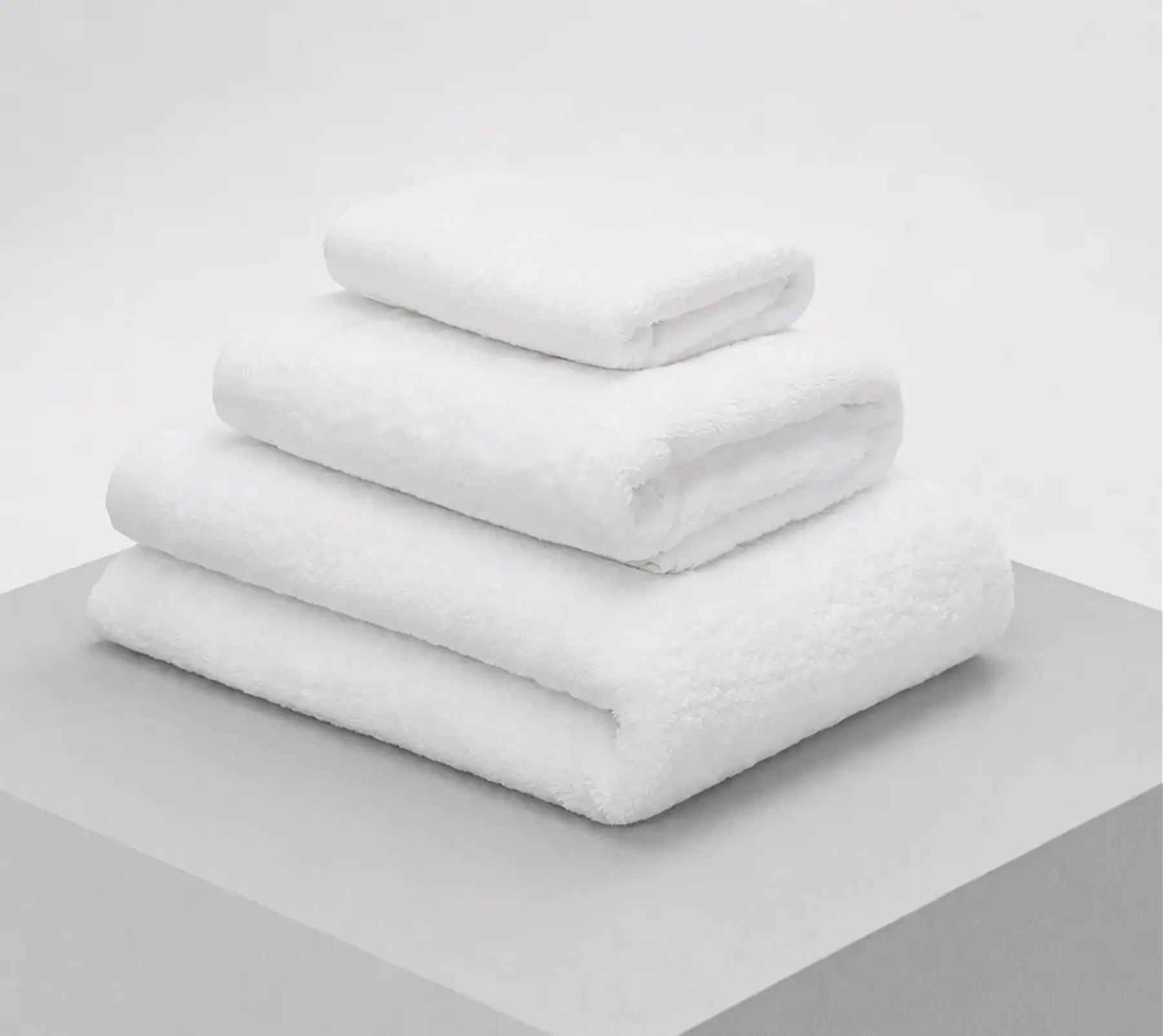 White bath linens in three different sizes, folded and stacked.
