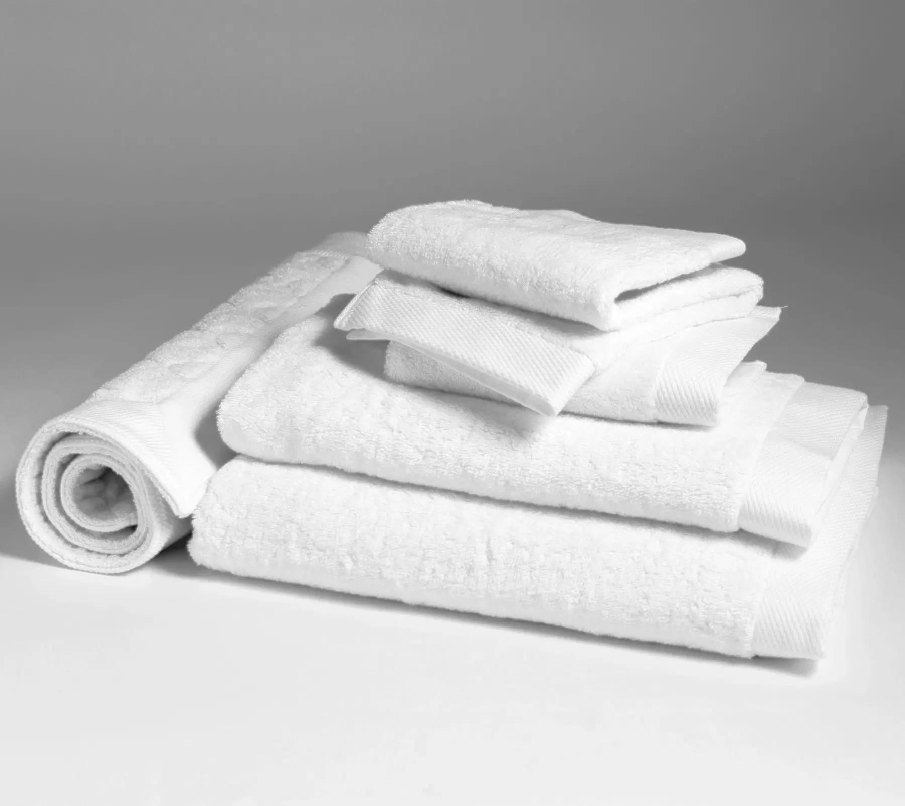White bath linen set and bath mat, folded and stacked.