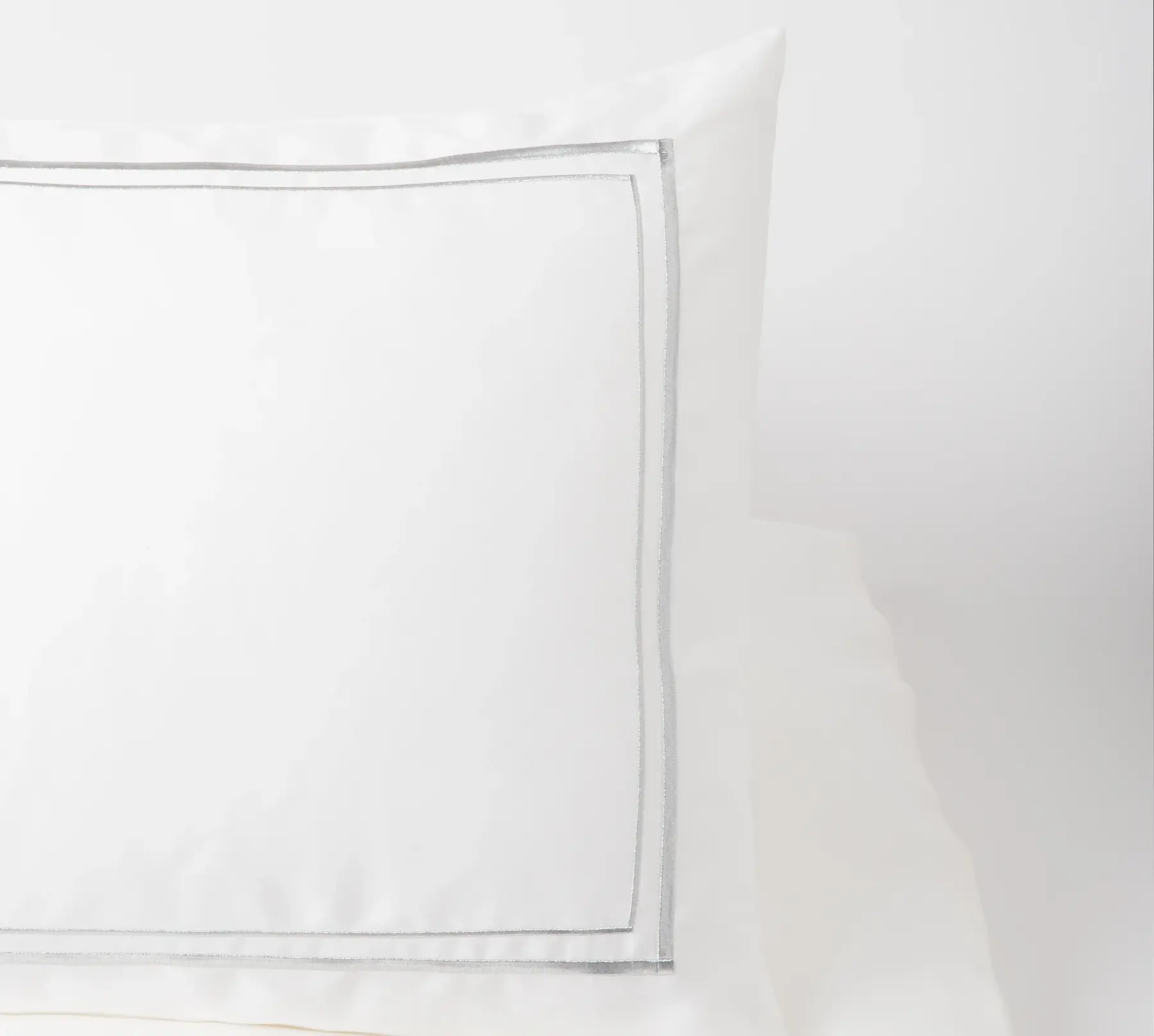 Detail of a white Beltrami pillowcase with a silver border.