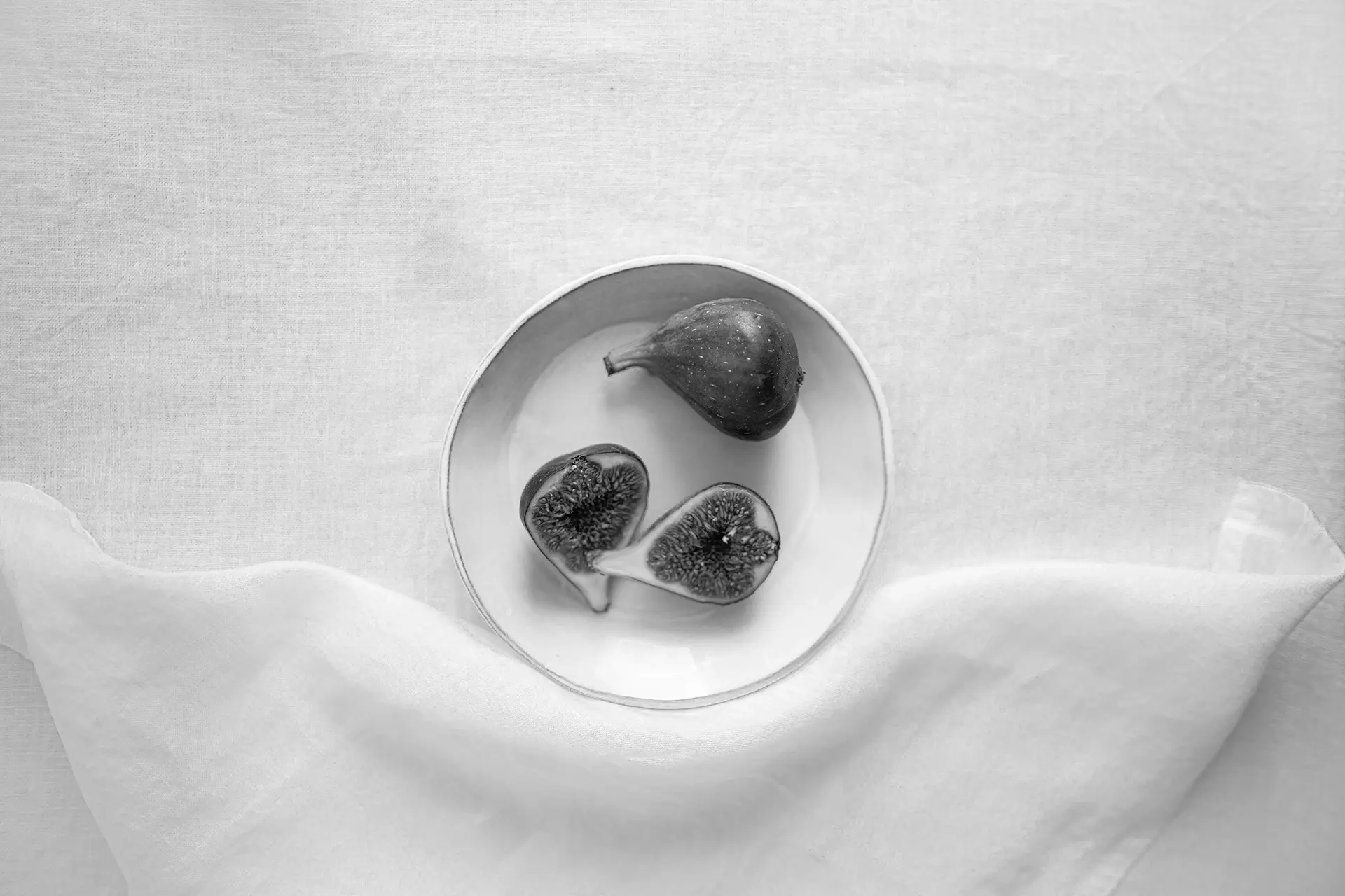 Table set with white Beltrami table linens and a bowl of figs